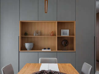 This stunning dining room features a built-in wooden shelving unit nestled within gray cabinetry, offering ample storage and display space.