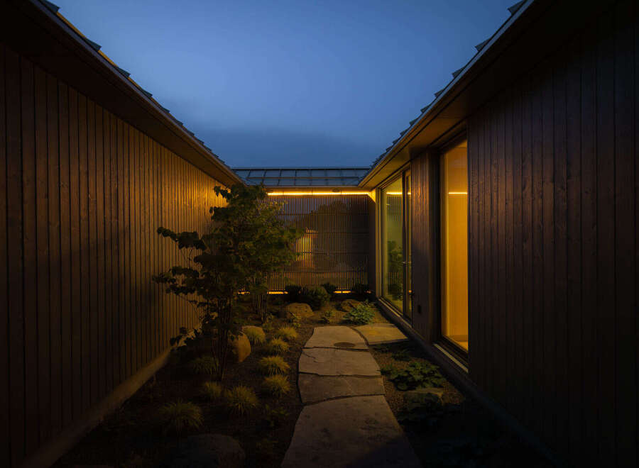 This modern home features a serene, secluded courtyard nestled between two dark wood-paneled walls.