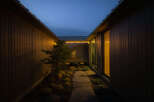 This modern home features a serene, secluded courtyard nestled between two dark wood-paneled walls.