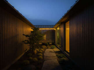 This modern home features a serene, secluded courtyard nestled between two dark wood-paneled walls.