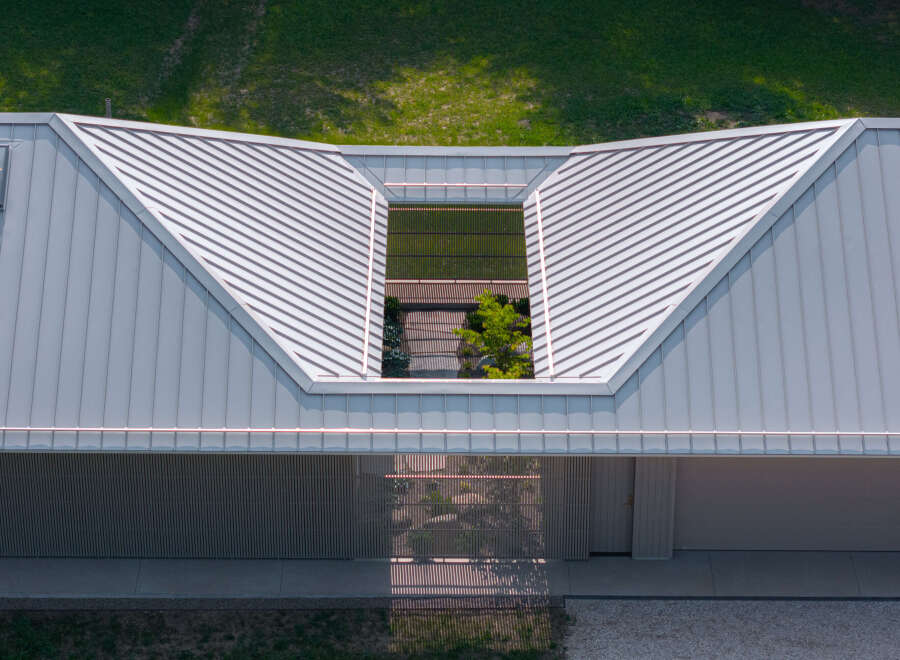 This modern home features a unique architectural design with a light gray metal roof and a central skylight that illuminates an interior courtyard.