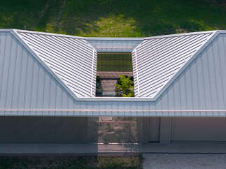 This modern home features a unique architectural design with a light gray metal roof and a central skylight that illuminates an interior courtyard.