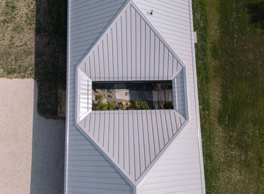 This property features a unique architectural design with a light gray metal roof and a central skylight illuminating an interior courtyard.