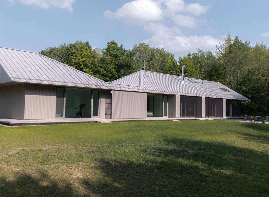 This stunning modern home boasts a sleek, contemporary design with a metal roof and large windows that offer abundant natural light.