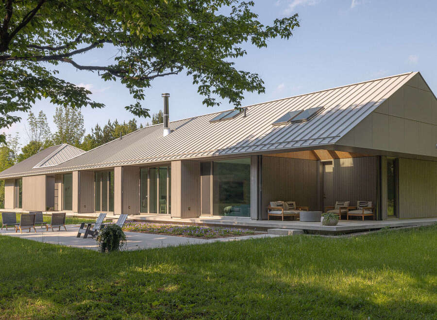 This stunning modern home boasts a sleek design with a metal roof and expansive windows, creating a seamless connection with the surrounding natural landscape.