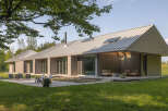 This stunning modern home boasts a sleek design with a metal roof and expansive windows, creating a seamless connection with the surrounding natural landscape.