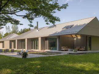 This stunning modern home boasts a sleek design with a metal roof and expansive windows, creating a seamless connection with the surrounding natural landscape.