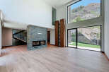 This stunning modern living room features a striking stone fireplace and expansive windows showcasing breathtaking mountain views.