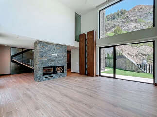 This stunning modern living room features a striking stone fireplace and expansive windows showcasing breathtaking mountain views.