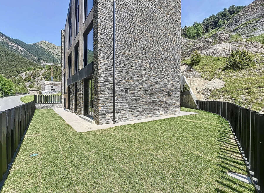 This modern mountain home boasts a stunning stone facade and expansive windows, perfectly blending with the natural landscape.