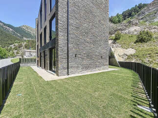 This modern mountain home boasts a stunning stone facade and expansive windows, perfectly blending with the natural landscape.