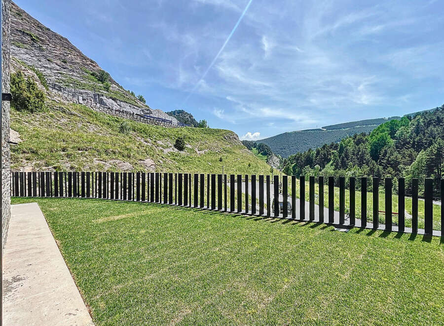Discover this exceptional property with a meticulously maintained lawn and modern fence, set against a breathtaking mountain backdrop.