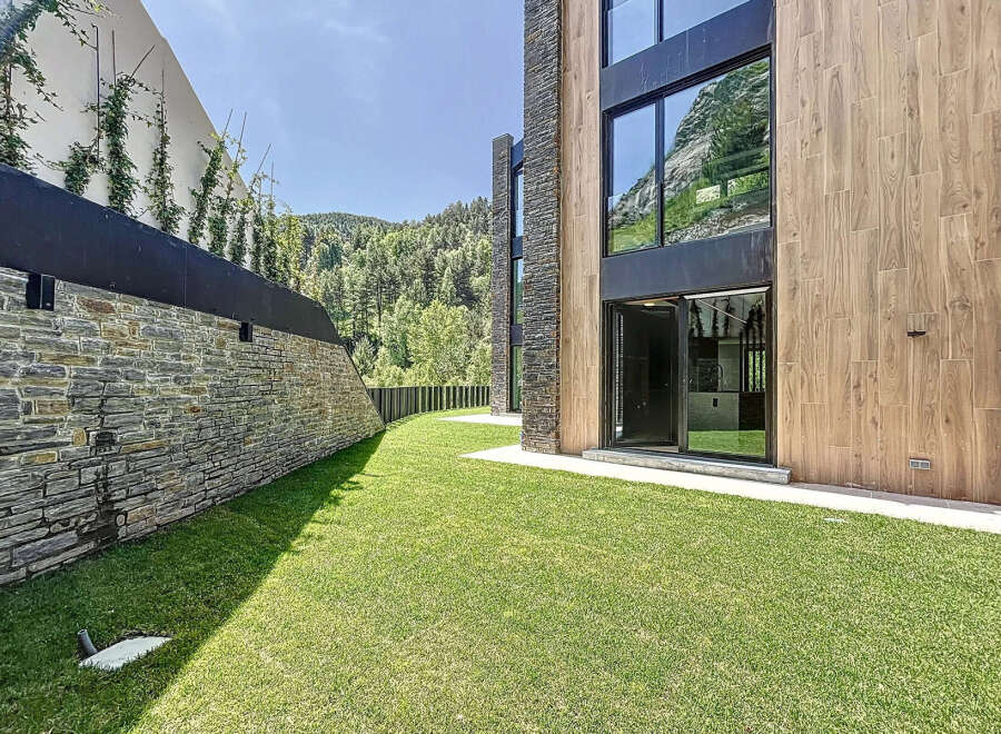 This modern home boasts a beautiful lawn and unique architectural design with stone and wood elements.