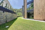 This modern home boasts a beautiful lawn and unique architectural design with stone and wood elements.