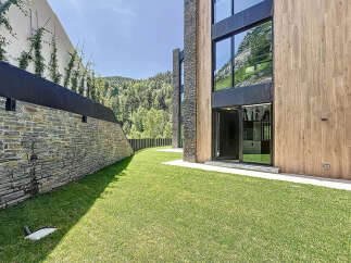 This modern home boasts a beautiful lawn and unique architectural design with stone and wood elements.