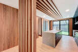 This modern kitchen features sleek wood paneling, a striking marble-topped island, and a unique slatted ceiling design.