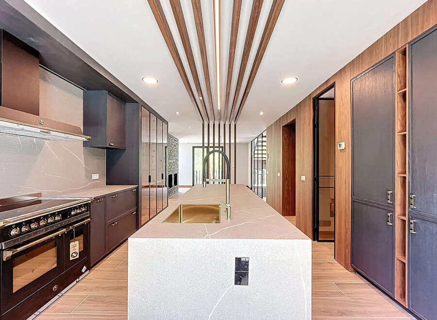 This modern kitchen features a large island with a sink, custom cabinetry, and a high-end Bertazzoni range.