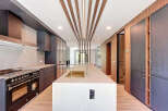 This modern kitchen features a large island with a sink, custom cabinetry, and a high-end Bertazzoni range.
