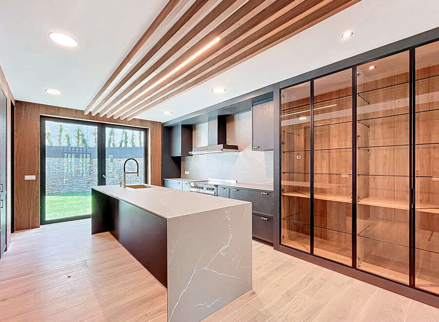 This contemporary kitchen boasts a spacious island with a unique marble countertop, providing ample space for food preparation and casual dining.
