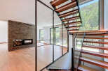 This modern home boasts a stunning staircase design with wooden steps and a glass railing, creating an open and airy feel.