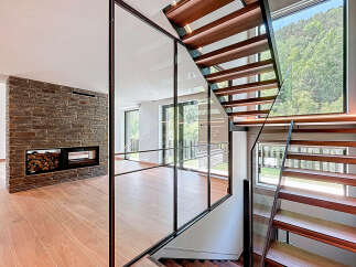 This modern home boasts a stunning staircase design with wooden steps and a glass railing, creating an open and airy feel.