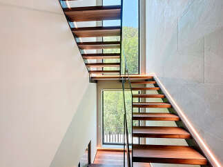 This modern home features a striking staircase design with open wooden treads and glass railings, creating a light and airy feel.