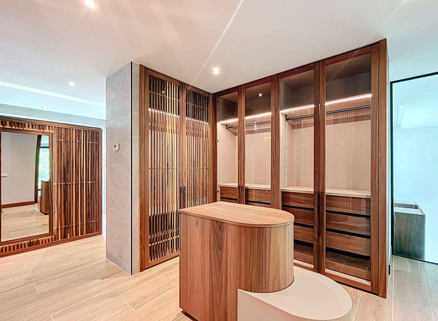 This walk-in closet features custom wood cabinets with glass doors, offering a blend of style and functionality.