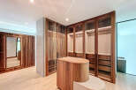 This walk-in closet features custom wood cabinets with glass doors, offering a blend of style and functionality.