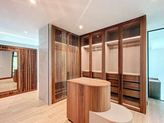 This walk-in closet features custom wood cabinets with glass doors, offering a blend of style and functionality.