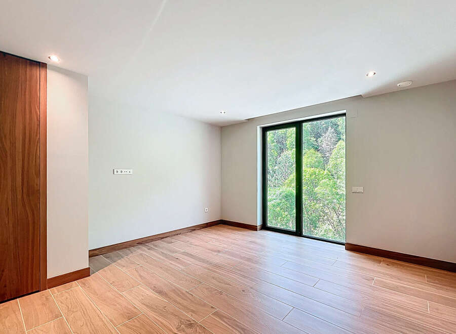 This spacious room features sleek, modern design elements, including stylish wood-look tile flooring and a striking wooden accent wall.