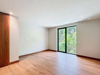 This spacious room features sleek, modern design elements, including stylish wood-look tile flooring and a striking wooden accent wall.
