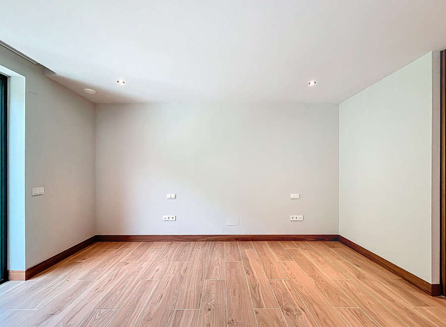 This empty room features beautiful wood-look tile flooring and a clean, minimalist aesthetic.