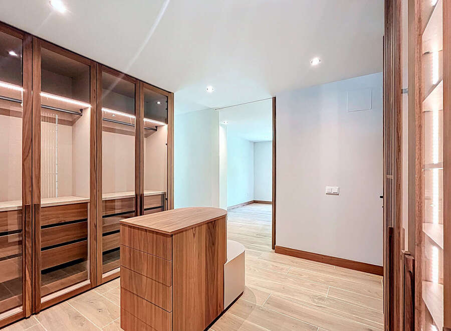 This walk-in closet features custom wood cabinetry with glass doors, offering ample storage space.