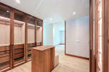 This walk-in closet features custom wood cabinetry with glass doors, offering ample storage space.