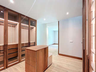 This walk-in closet features custom wood cabinetry with glass doors, offering ample storage space.