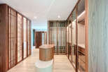 This custom walk-in closet features elegant wood cabinets with glass doors, showcasing an organized display of clothing and accessories.