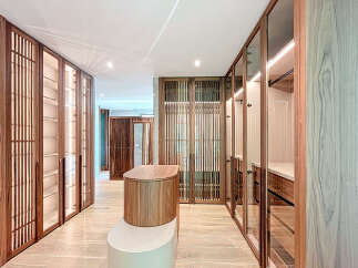 This custom walk-in closet features elegant wood cabinets with glass doors, showcasing an organized display of clothing and accessories.