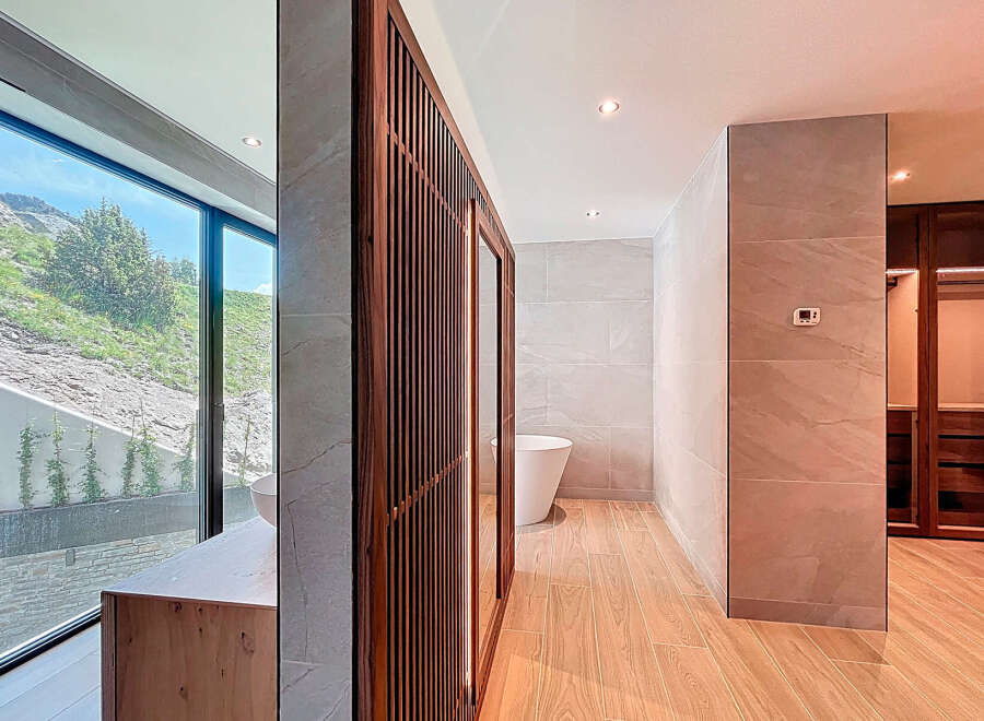 This bathroom features a large window with scenic views, wood-look tile flooring, and a modern vanity.