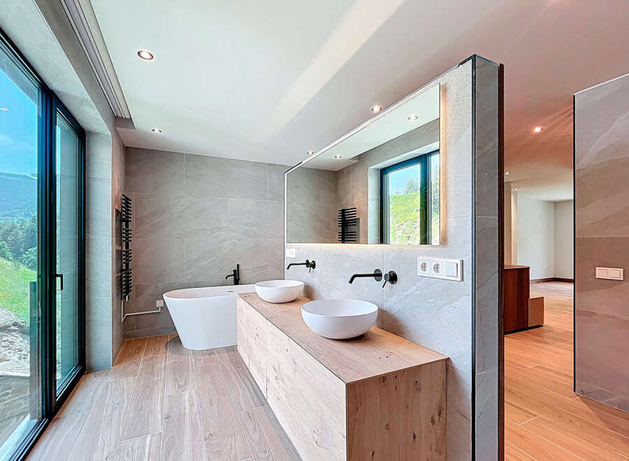 This modern bathroom features a freestanding bathtub and a double vanity with vessel sinks, complemented by sleek, matte black fixtures.