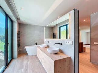 This modern bathroom features a freestanding bathtub and a double vanity with vessel sinks, complemented by sleek, matte black fixtures.