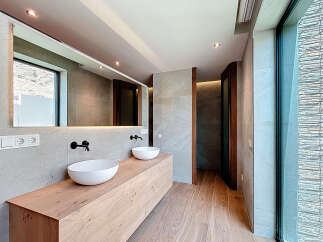 This modern bathroom features a double sink vanity with sleek black faucets, complemented by a large mirror and natural wood accents.