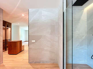This modern bathroom showcases a walk-in shower with sleek, gray tiling and a black rainfall showerhead.