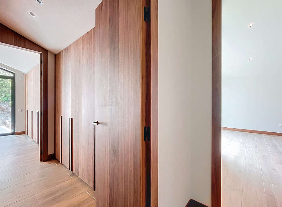 This modern home features a hallway with sleek wooden built-in cabinets and wood flooring.