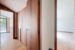 This modern home features a hallway with sleek wooden built-in cabinets and wood flooring.