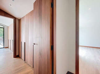 This modern home features a hallway with sleek wooden built-in cabinets and wood flooring.