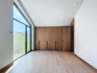 This modern bedroom boasts a wall of sleek, wooden built-in wardrobes, offering ample storage space.