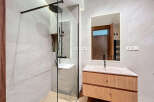 This modern bathroom features a sleek, glass-enclosed shower with black fixtures, complemented by a stylish vanity with a light wood finish.