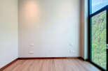 This is an empty room with hardwood floors, light gray walls, and modern dark wood trim.
