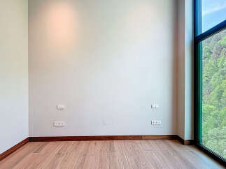 This is an empty room with hardwood floors, light gray walls, and modern dark wood trim.