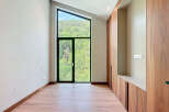 This is an interior of a modern property featuring a large, triangular window with scenic views of lush greenery.